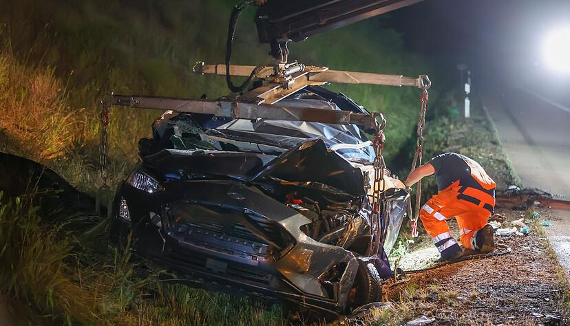 Ein Mitarbeiter eines Abschleppunternehmens bereitet das Wrack eines Pkw nach dem schweren Verkehrsunfall f&uuml;r die Bergung vor.