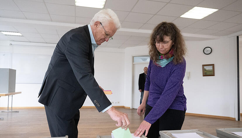 Der Ministerpräsident von Baden-Württemberg Winfried Kretschmann (Bündnis 90/Die Grünen, l) wirft in einem Wahlraum im Rathaus im Sigmaringer Stadtteil Laiz einen Stimmzettel in eine Wahlurne, daneben steht eine Wahlhelferin. Der Ministerpräsident von Baden-Württemberg Winfried Kretschmann (Bündnis 90/Die Grünen, l) wirft in einem Wahlraum im Rathaus im Sigmaringer Stadtteil Laiz einen Stimmzettel in eine Wahlurne, daneben steht eine Wahlhelferin.