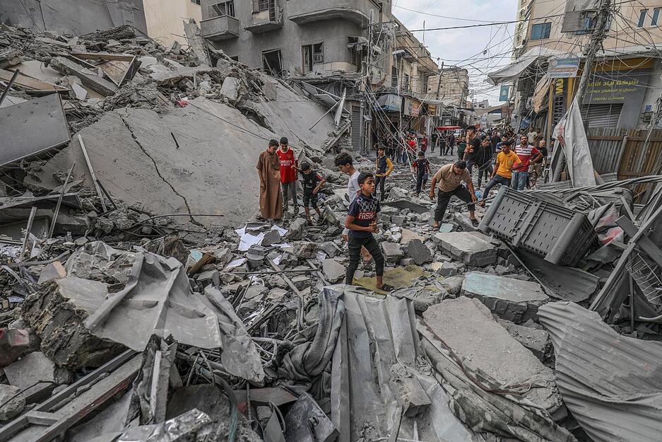 Palästinenser laufen nach einem israelischen Luftangriff im Gazastreifen zwischen den Trümmern eines zerstörten Gebäudes umher.