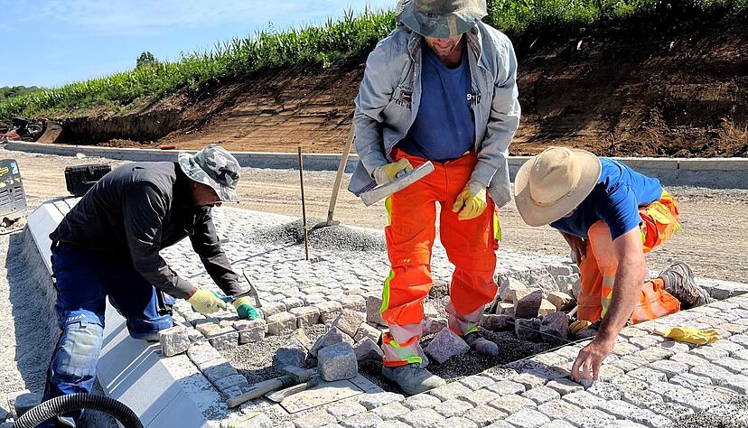 Mitarbeiter der Firma Lukas Gläser pflastern eine der neuen Verkehrsinseln.