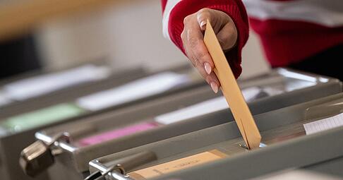 Eine Wählerin wirft einen Wahlschein in eine Urne.