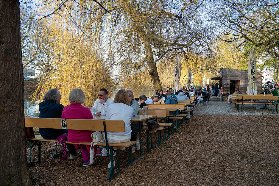 Frühlingserwachen am Neckar in Heilbronn: Menschen genießen ein kühles Getränk im Freien.