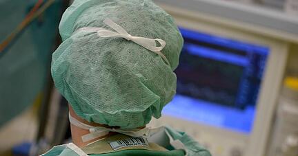 Ein Mediziner schaut w&auml;hrend einer Operation auf einen &Uuml;berwachungs-Monitor.