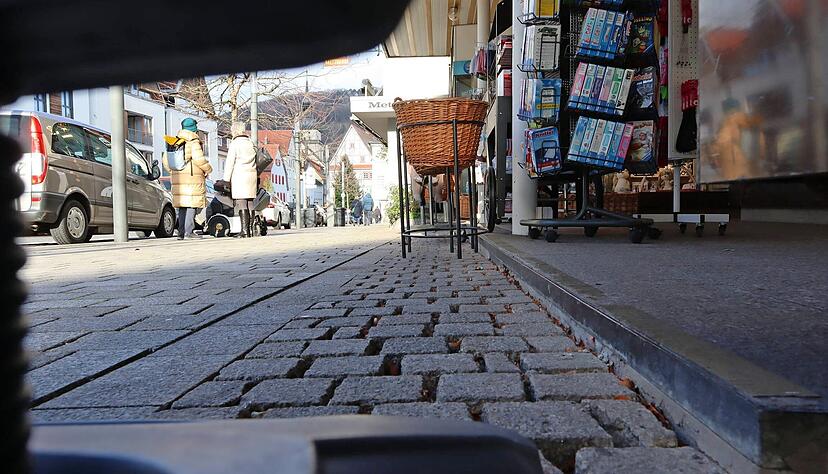 Kleine Stufen sind Barrieren f&uuml;r
Menschen, die im Rollstuhl sitzen. Die Pflastersteine k&ouml;nnten blinde Menschen mit Tastst&ouml;cken als Leitmarken nutzen. Allerdings stehen hier Warenaufsteller im Weg.