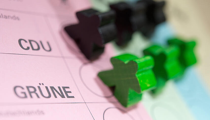Schwarze und grüne Spielfiguren stehen auf einem Wahlzettel für die Landtagswahl in Baden-Württemberg. Schwarze und grüne Spielfiguren stehen auf einem Wahlzettel für die Landtagswahl in Baden-Württemberg.