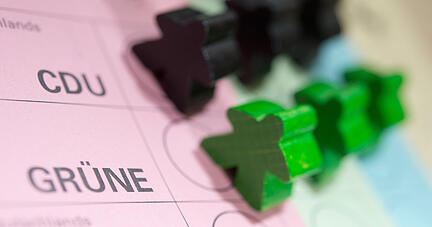 Schwarze und gr&uuml;ne Spielfiguren stehen auf einem Wahlzettel f&uuml;r die Landtagswahl in Baden-W&uuml;rttemberg.