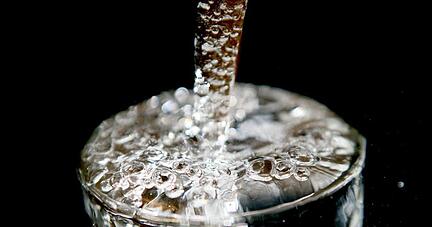Ein überlaufendes Glas, in das Trinkwasser läuft.