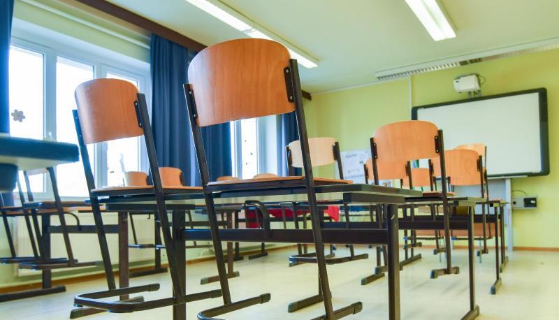In einem leeren Unterrichtsraum an einer Schule sind die Stühle auf einen Tisch gestellt.