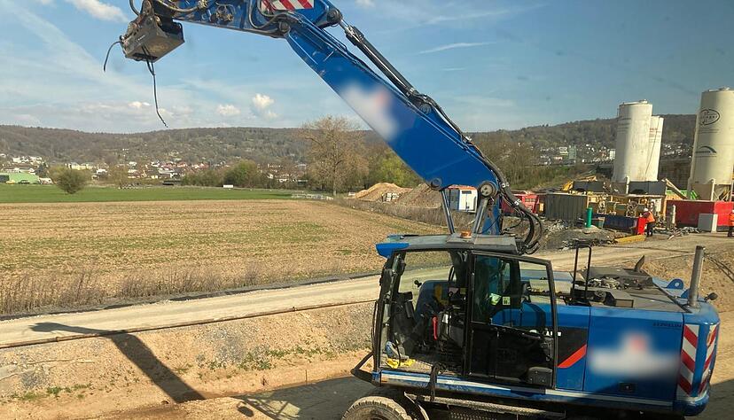 Der besch&auml;digte Bagger steht an einer Baustelle neben den Bahngleisen.