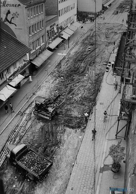 Die Kaiserstraße ist für den Verkehr gesperrt und nur noch für Fußgänger passierbar.  Die alten Straßenbahnschienen werden entfernt. Aufnahme aus dem Jahr 1961.