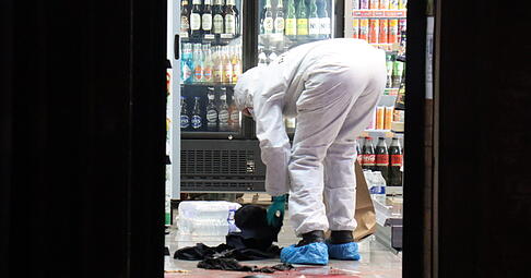 Ein Polizist arbeitet an der Spurensicherung in einem Kiosk in Mannheim.
