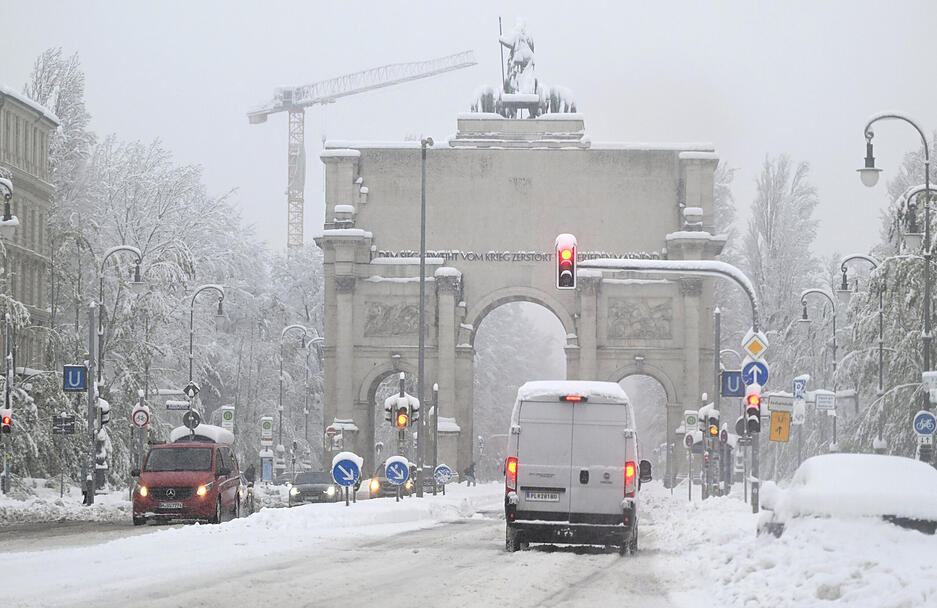 Der Verkehr rollt vorbei am verschneiten Siegestor.