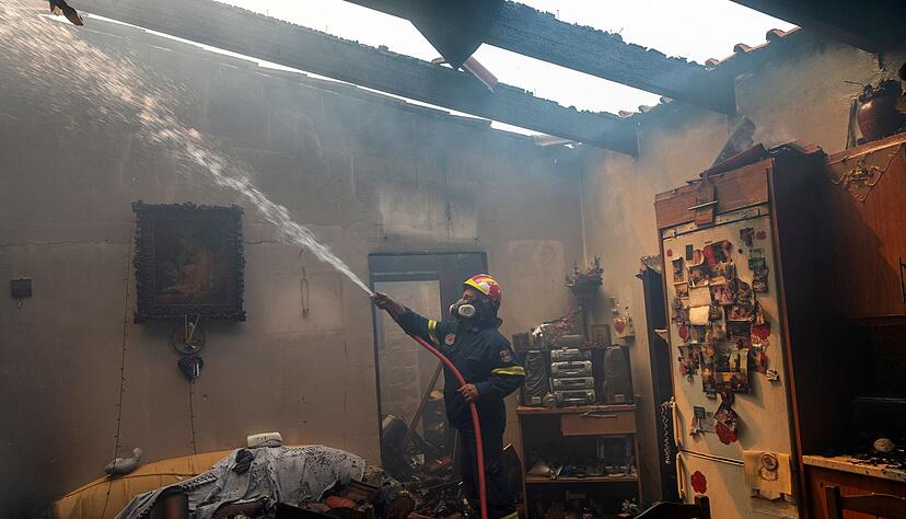 Ein Feuerwehrmann löscht ein Haus im Dorf Hasia in der Nähe von Athen.