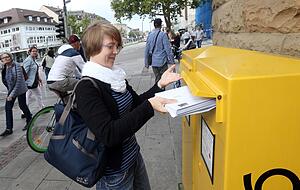 Eine Kundin beim Einwurf von Briefen an der Poststelle an der Allee. Foto: Veigel