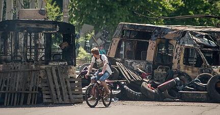 Ein Fahrradfahrer passiert ausgebrannte Buswracks im ostukrainischen Kramatorsk. Foto: Roman Pilipey Ein Fahrradfahrer passiert ausgebrannte Buswracks im ostukrainischen Kramatorsk. Foto: Roman Pilipey