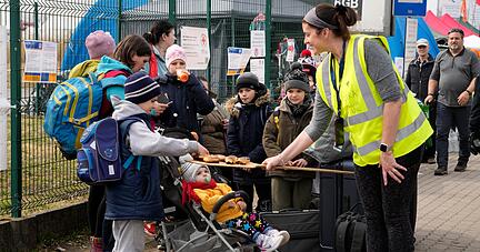 Eine Freiwillige bietet Gefl&uuml;chteten aus der Ukraine Donuts an, bevor sie den Grenz&uuml;bergang in Medyka im S&uuml;dosten Polens verlassen. Foto: dpa