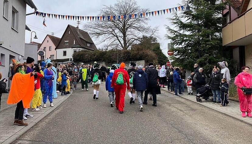 Die ersten Narren warten am Stra&szlig;enrand, einige laufen noch in Richtung Umzugsanfang.