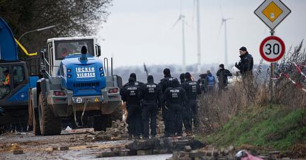 Schwere Räumfahrzeuge entfernen im Beisein der Polizei die von Klimaaktivisten errichteten Barrikaden.