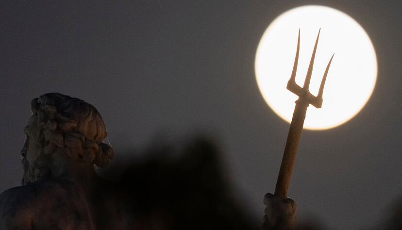 Hinter der Poseidon-Statue in Kopenhagen ist am Himmel ein großer Vollmond zu sehen. Hinter der Poseidon-Statue in Kopenhagen ist am Himmel ein großer Vollmond zu sehen.