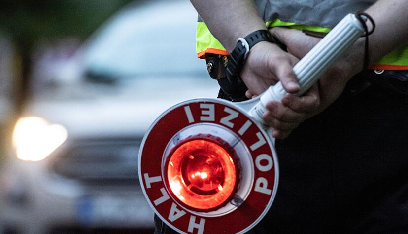 Ein Polizist hält bei einer Verkehrskontrolle eine Winkerkelle in der Hand. Ein Polizist hält bei einer Verkehrskontrolle eine Winkerkelle in der Hand.
