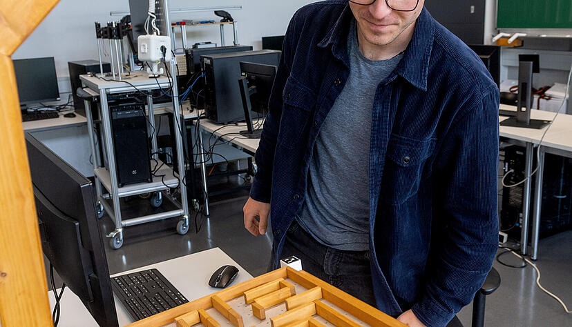 Die KI steuert eine Kugel durch ein Holzlabyrinth, beobachtet von Simon Heuschkel. Die KI steuert eine Kugel durch ein Holzlabyrinth, beobachtet von Simon Heuschkel.