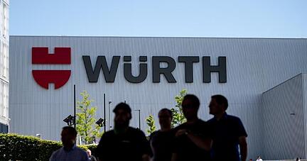 Mitarbeiter des Handelskonzern Würth stehen vor dem Logo des Unternehmens.