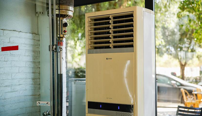 Athen: Eine mobile Klimaanlage steht im verglasten Innenraum eines Caf&eacute;s. (Archivbild)