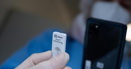 Eine Mitarbeiterin einer Schnellteststation scannt einen Schnelltest.