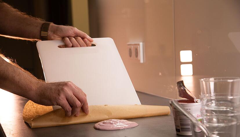 Schritt 1: Backpapier und Schneidebrett am Klecks ansetzen. Schritt 1: Backpapier und Schneidebrett am Klecks ansetzen.