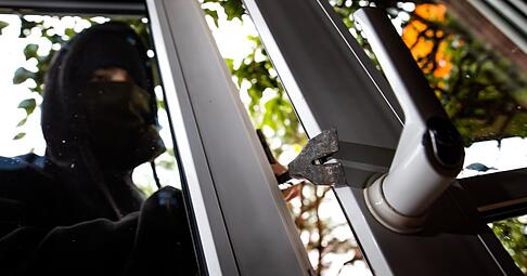 Ein Mann mimt einen Einbrecher und benutzt ein Brecheisen, um eine gekippte Terrassent&uuml;r aufzuhebeln. (Symbolbild).