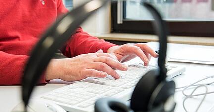 Ein Mitarbeiter tippt auf einer Computer-Tastatur.