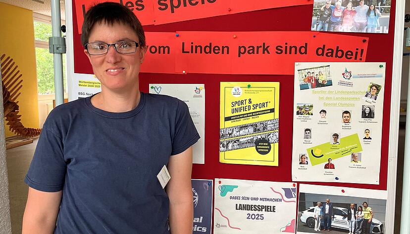 Christiane Gurr ist erstmals bei Special Olympics Landesspielen dabei und posiert stolz vor der Infotafel in der Lindenparkschule, wo sie arbeitet.