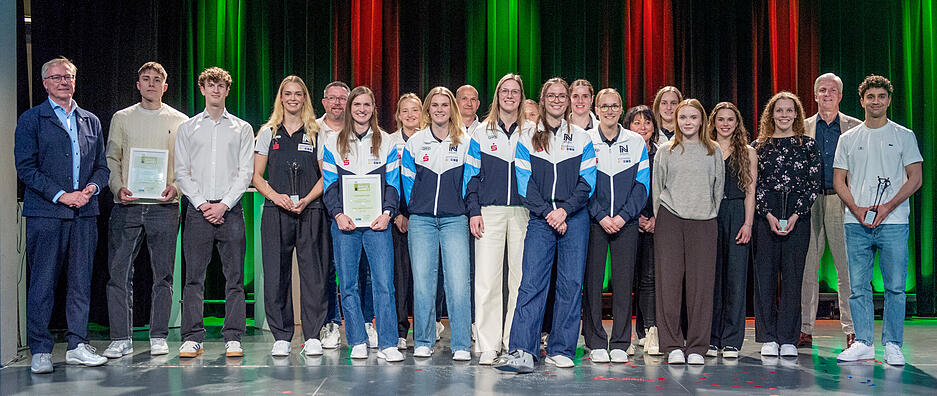 Eingerahmt von Stimme-Verleger Tilmann Distelbarth (links) und Chefredakteur und Fest-des-Sports-Moderator Uwe Ralf Heer (rechts hinten) posierten die besten Sportlerinnen und Sportler des Jahres 2025 auf der B&uuml;hne &bdquo;Unter der Pyramide&ldquo; der Kreissparkasse Heilbronn.