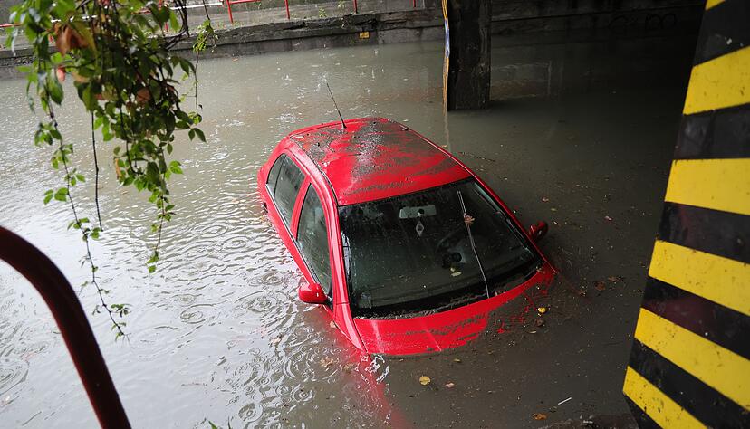 Ein Auto steht unter einer Bahnlinie in einer &uuml;berfluteten Unterf&uuml;hrung im Wasser.