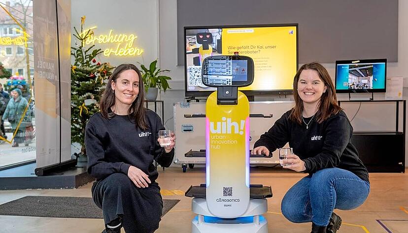 Lena Ahner (links) und Nathalie Alischer mit dem Roboter Kai im Urban Innovation Hub. Das Angebot in der Ladenzeile wird ständig variiert.
Foto: Mario Berger Lena Ahner (links) und Nathalie Alischer mit dem Roboter Kai im Urban Innovation Hub. Das Angebot in der Ladenzeile wird ständig variiert.
Foto: Mario Berger
