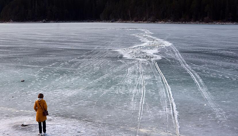 Eine Frau steht am Ufer des zugefrorenen Eibsees, nahe der Stelle an der am Nachmittag mehrere Menschen im Eis eingebrochen waren. Eine Frau steht am Ufer des zugefrorenen Eibsees, nahe der Stelle an der am Nachmittag mehrere Menschen im Eis eingebrochen waren.