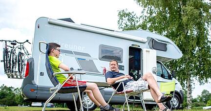 Urlauber aus Bayern sitzen auf einem Campingplatz vor ihrem Wohnmobil. Urlauber aus Bayern sitzen auf einem Campingplatz vor ihrem Wohnmobil.