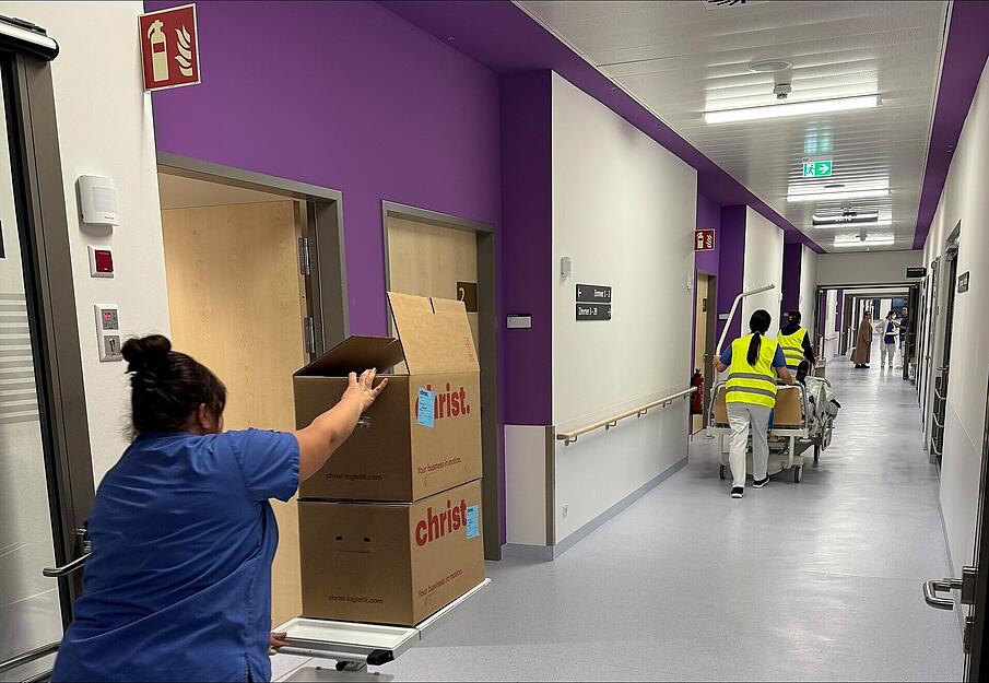 Pflegekr&auml;fte rollen Patientenbetten, Mobiliar und Kisten in den neuen Klinikabschnitt.