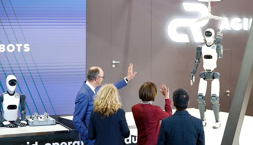 Bundeskanzler Friedrich Merz winkt einem Roboter zu &ndash; die Zukunft winkt zur&uuml;ck.