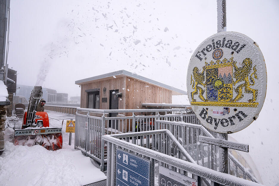 Neuschnee in Bayern: Eine Frau räumt Schnee auf der Aufsichtsplattform der Zugspitze.