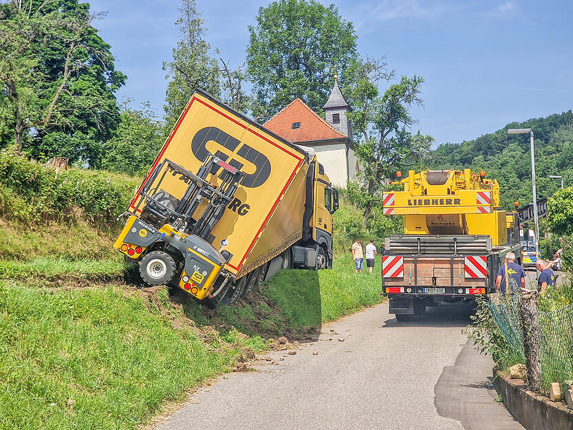 Der mit Pflastersteinen beladene Lkw soll in Haßmersheim von einem Schwerlastkran vor dem Absturz gerettet werden. Der mit Pflastersteinen beladene Lkw soll in Haßmersheim von einem Schwerlastkran vor dem Absturz gerettet werden.