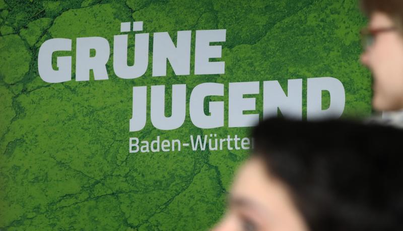 Mitglieder der Grünen Jugend Baden-Württemberg stehen bei ihrer Landesmitgliederversammlung vor dem Logo ihrer Partei.
