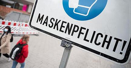 Zwei Passantinnen in der Heilbronner Fußgängerzone hinter einem Maskenpflicht-Hinweisschild.