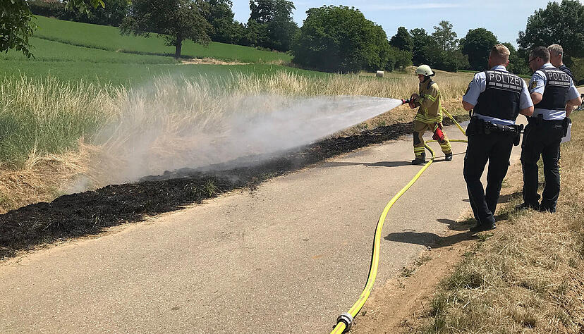 Ein Feuerwehrmann löscht die am Freitag in Brand geratene Wiesenfläche bei Kirchhausen. Ein Feuerwehrmann löscht die am Freitag in Brand geratene Wiesenfläche bei Kirchhausen.
