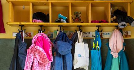 Jacken und Taschen hängen im Eingangsbereich in einem Kindergarten.