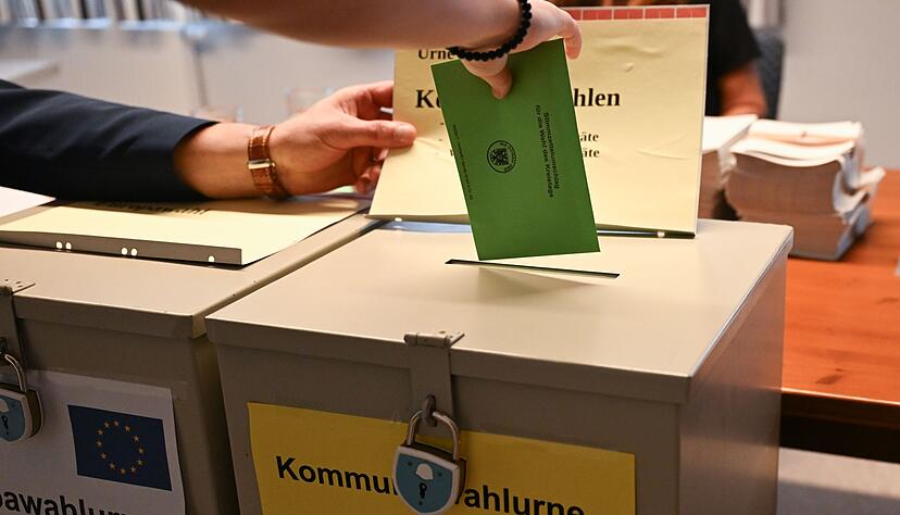 In einem Wahllokal steckt eine W&auml;hlerin ihren Stimmzettel f&uuml;r die Kommunalwahl in eine Wahlurne.