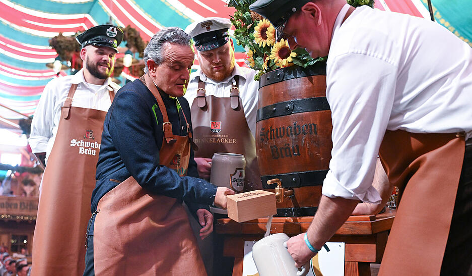 Frank Nopper (l, CDU), Oberbürgermeister von Stuttgart, sticht beim Stuttgarter Volksfest Cannstatter Wasen zur Eröffnung das erste Fass Bier an.