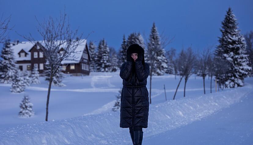 Eine Frau spaziert durch eine verschneite Landschaft in Tschechien.