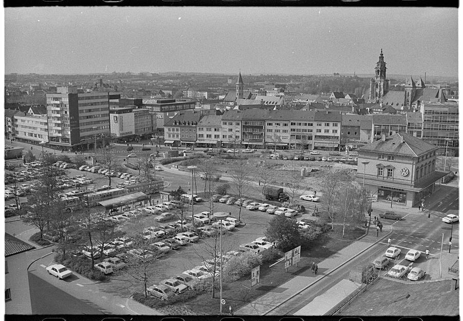 April 1972: Diese Ansicht auf den zentralen Platz vom Heilbronner Sparkassengebäude aus fotografiert. Im Hintergrund rechts ist der Turm der Kilianskirche sichtbar, links säumen Geschäftshäuser die Fleiner Straße. Das Hallenbad ist im Februar gesprengt, die Lücke gibt den Blick auf Wohn- und Geschäftshäuser entlang der Hohe Straße frei.