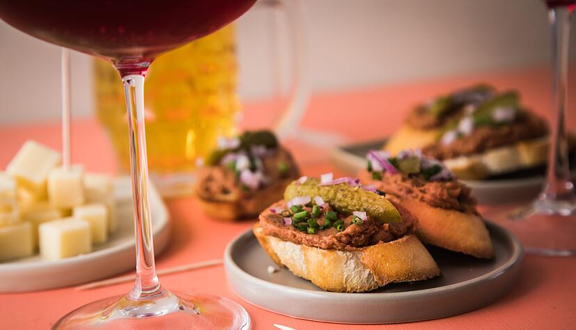 Ob als Fingerfood oder an der Bar: Borrelhapjes mit Filet Americain auf Baguette werden gern mit Cornichons, Zwiebeln und K&auml;sew&uuml;rfeln zu einem Drink gereicht.